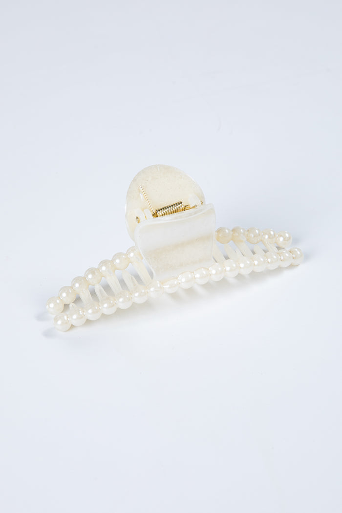 White hair clip with pearl details on a light gray background