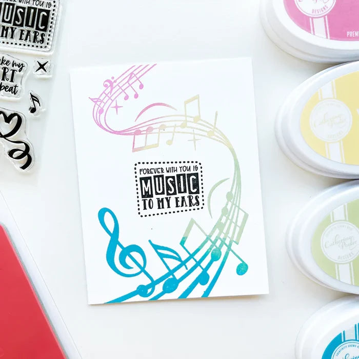 Catherine Pooler - Background Stamp - On Staff. Add some dancing notes to your card background with the On Staff Background Stamp. This red rubber stamp features a winding music staff pattern with notes and musical icons. Available at Embellish Away located in Bowmanville Ontario Canada. Card example by brand ambassador.