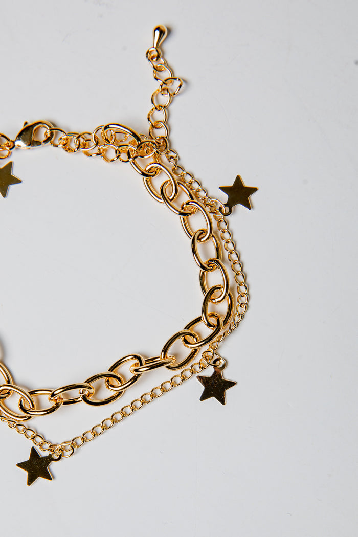 Gold chain bracelet with star charms on a light gray background