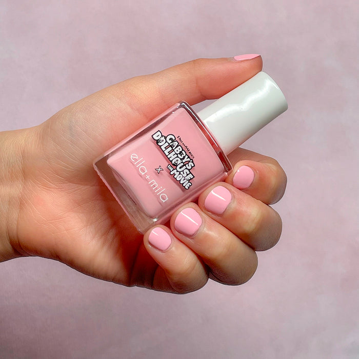 Gabby's Dollhouse light pink shimmer nail polish on a light skin tone, hand holding the bottle