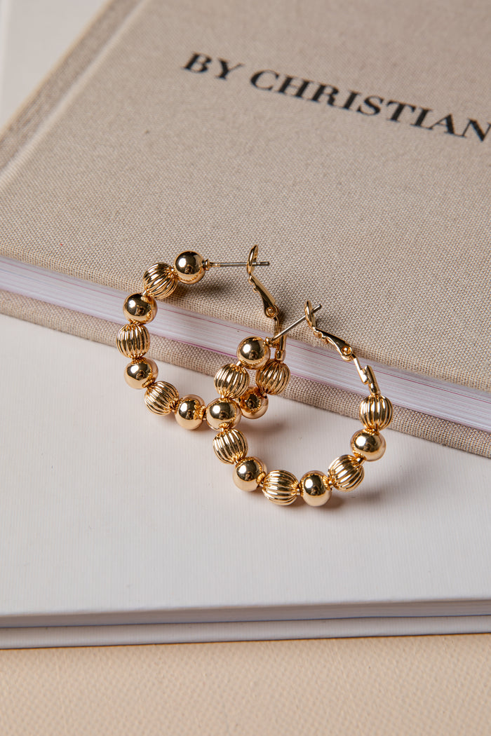 Gold hoop earrings on a book with 'By Christian Dior' text