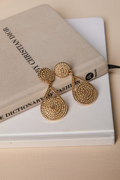 Gold earrings on a book with a beige cover