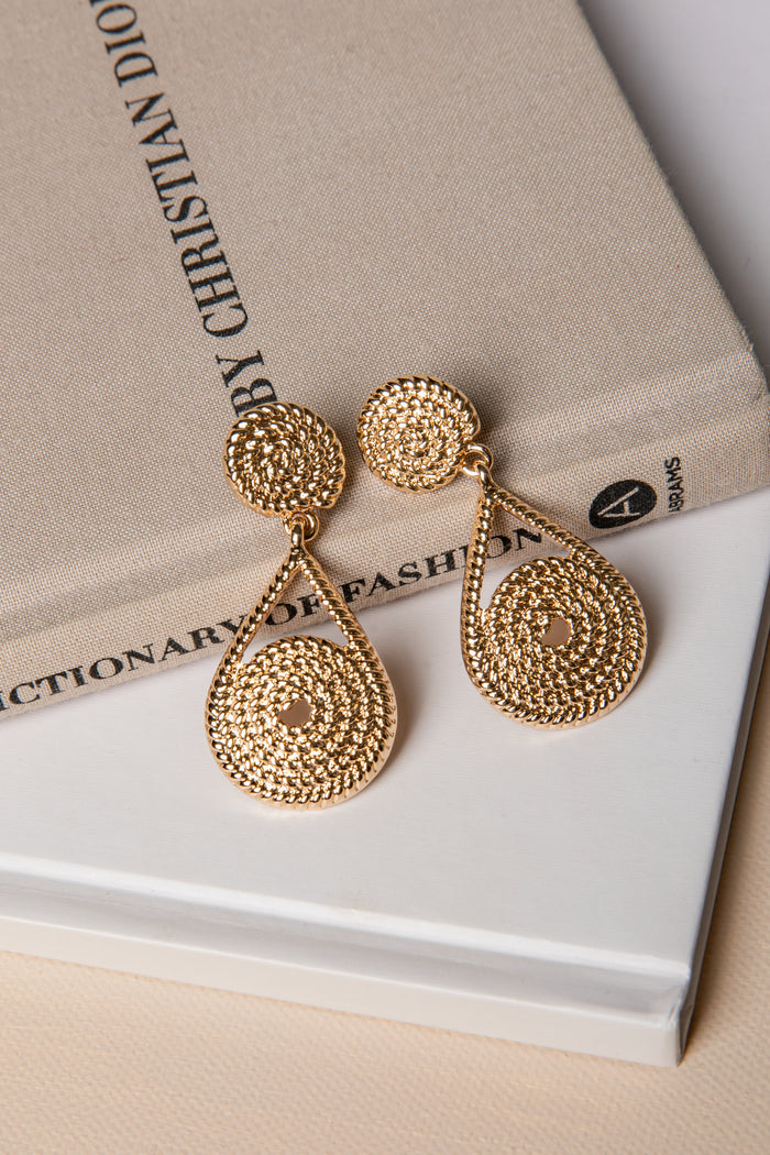 Gold earrings on a book with 'Christian Dior' text