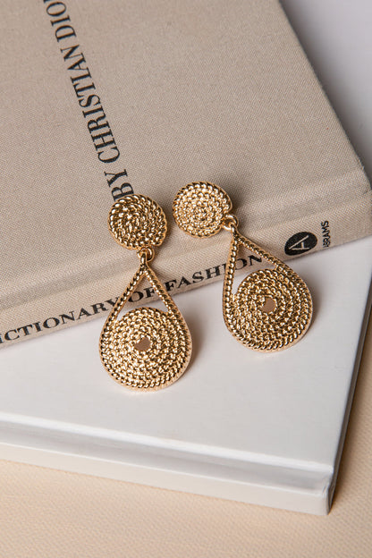 Gold earrings on a book with 'Christian Dior' text