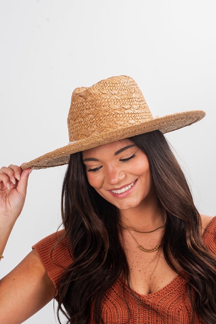 Woman wearing a straw hat against a plain background
