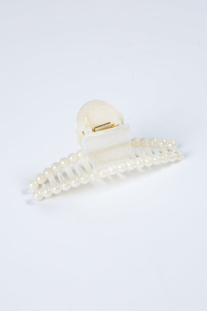 White hair clip with pearl details on a light gray background