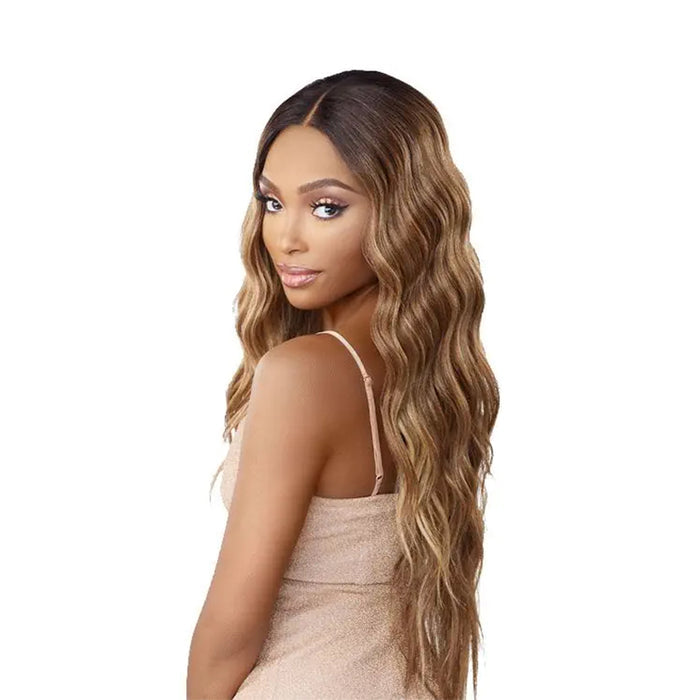 SENSATIONNEL butta lace unit 29 wig long wavy honey blonde with dark roots and center part on model