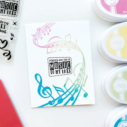 Catherine Pooler - Background Stamp - On Staff. Add some dancing notes to your card background with the On Staff Background Stamp. This red rubber stamp features a winding music staff pattern with notes and musical icons. Available at Embellish Away located in Bowmanville Ontario Canada. Card example by brand ambassador.