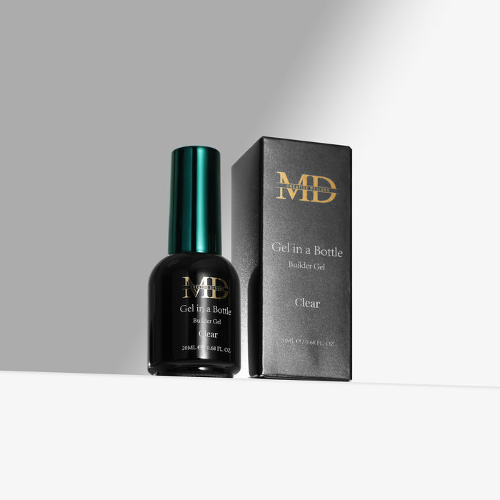 A bottle of MD Clear Gel In A Bottle nail gel stands next to its black packaging box with gold lettering on a clean white surface against a gray background.