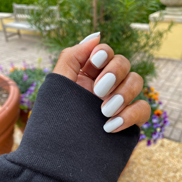 Hand showing nails painted in Cloudy Skies for a soft grey polished manicure in natural outdoor lighting