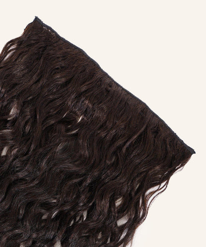 A close-up of Curly Perfect Crown Hair Extensions by Perfect Locks in Honey Blonde , featuring soft waves and a shiny finish.#color_natural-black-(1B)