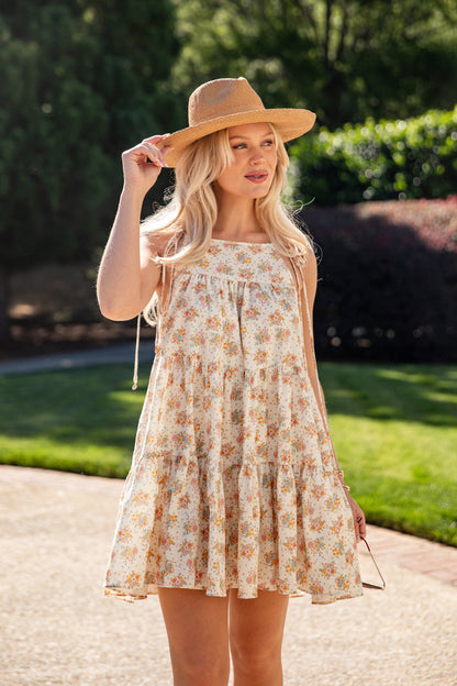 Woman wearing a floral dress and wide-brimmed hat outdoors
