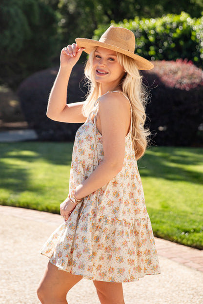 Woman wearing a floral dress and straw hat outdoors on a sunny day