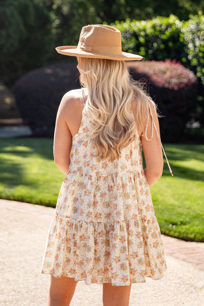 Woman wearing a floral dress and straw hat in an outdoor setting