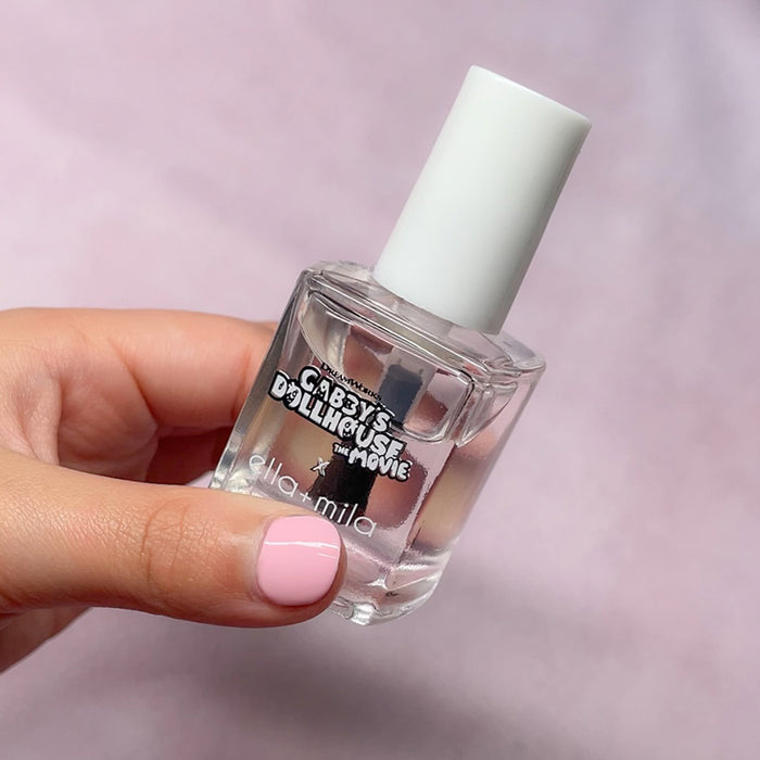 Gabby's Dollhouse clear top coat on a pink manicure, holding the bottle