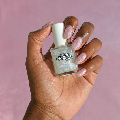 Gabby's Dollhouse silver glitter nail polish on a medium skin tone, hand holding the bottle