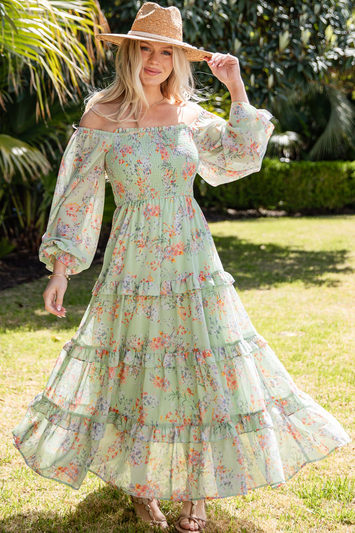 Woman in a floral dress and hat standing in a garden