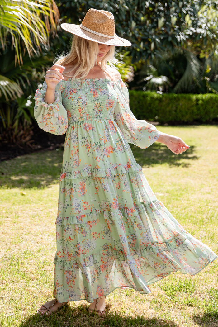 Woman in a floral dress and hat standing in a garden