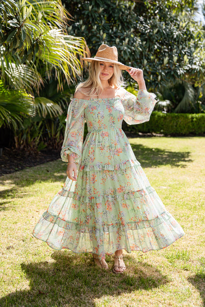 Woman in a floral dress and hat standing in a garden