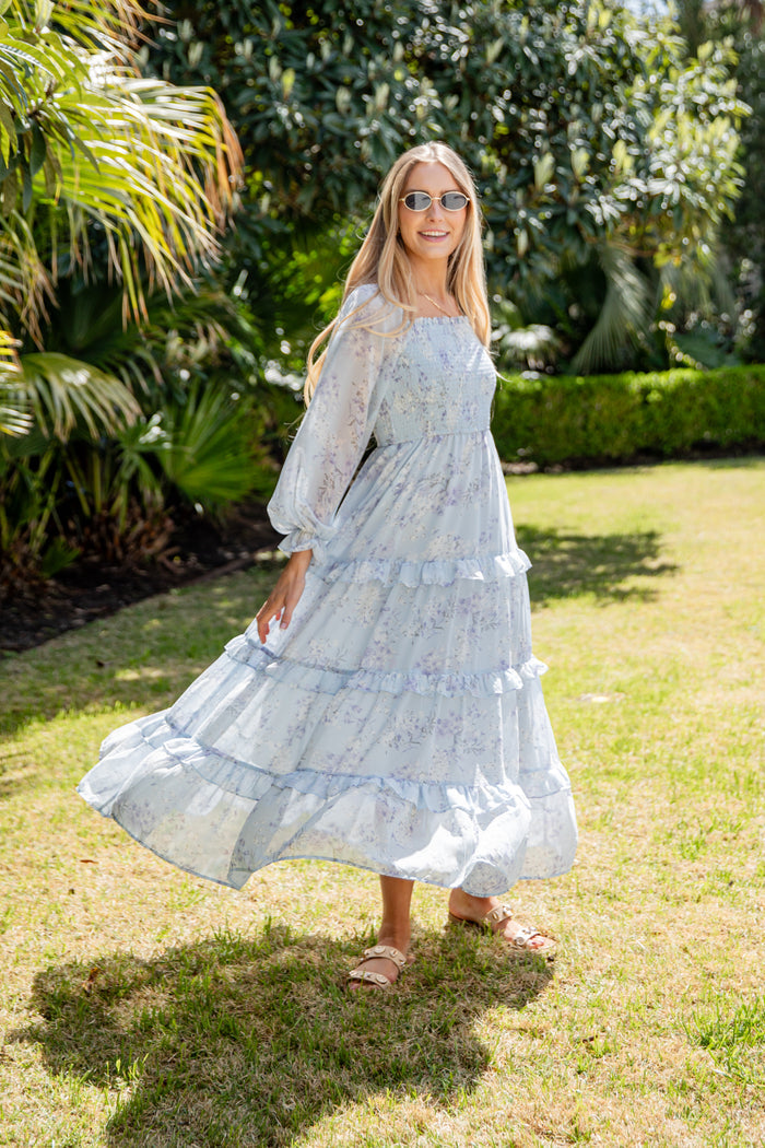 Woman in a light blue dress standing in a garden