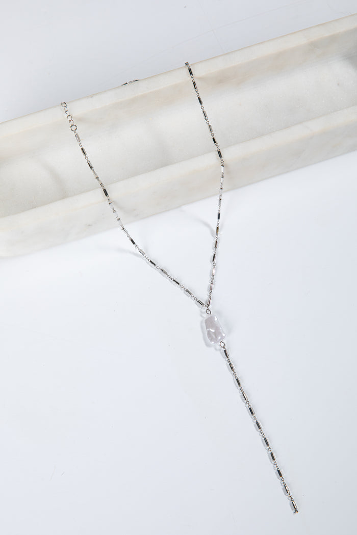 Silver necklace with a clear pendant on a marble surface