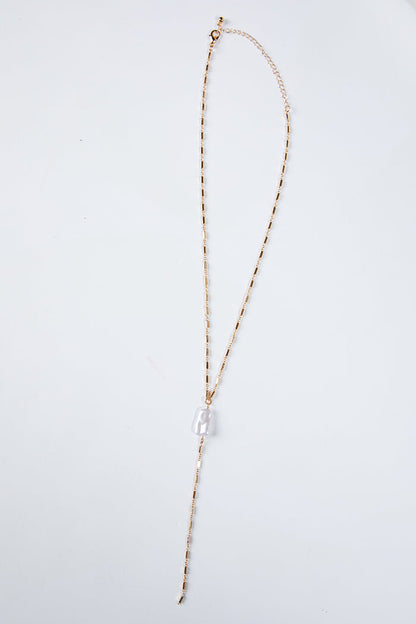 Long necklace with a clear pendant on a light gray background