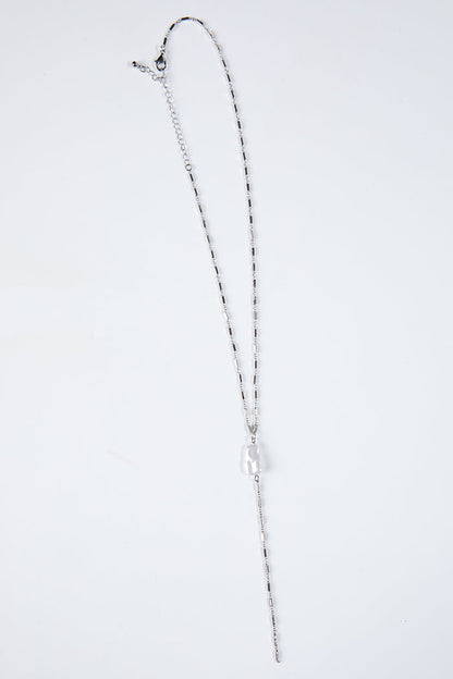 Silver necklace on a light gray background