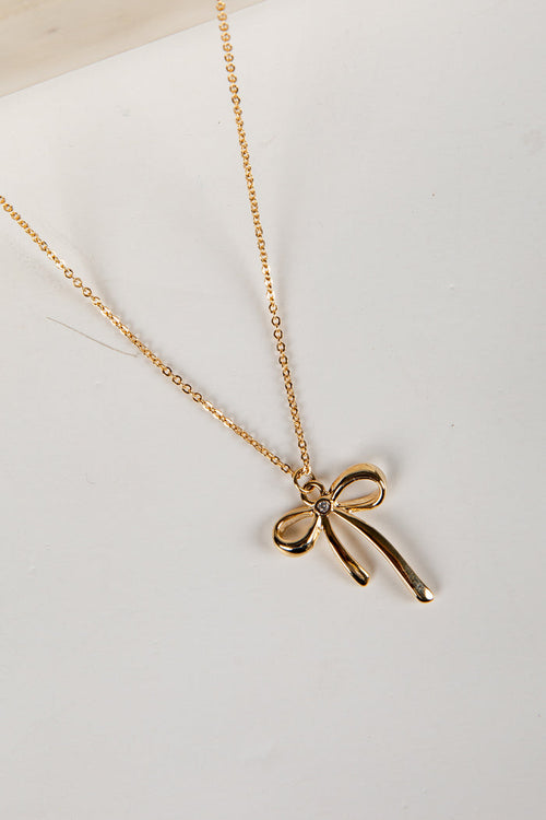 Gold bow-shaped pendant necklace on a white background