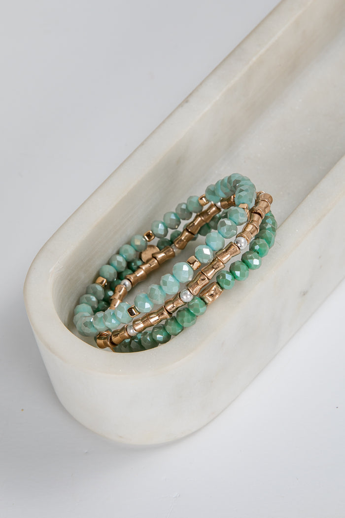 Set of green beaded bracelets on a white marble surface