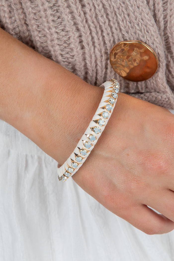Close-up of a person's wrist wearing a silver bracelet with a textured sweater background