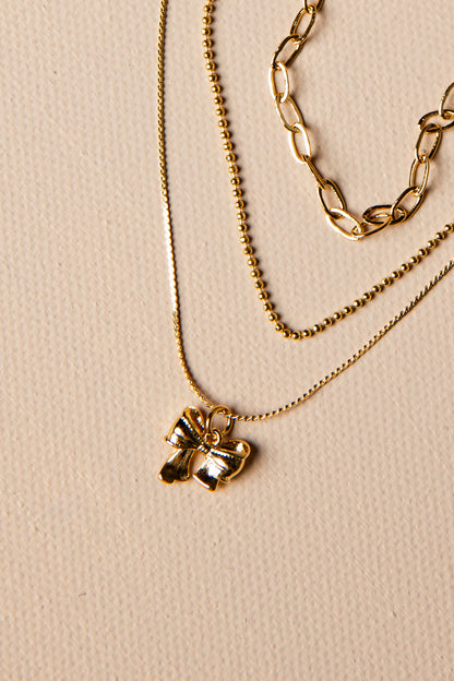 Three gold necklaces with different designs on a beige background