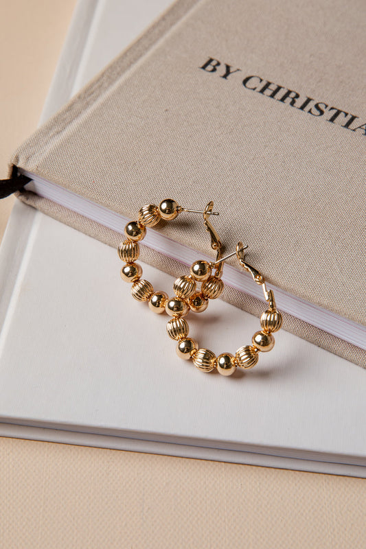 Gold hoop earrings on a book with 'By Christian Dior' text