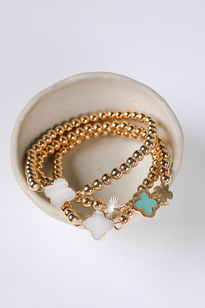 Gold bracelets with charms on a white background