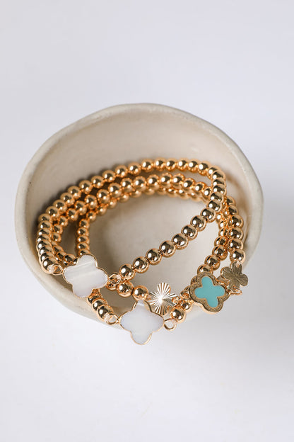 Gold bracelets with charms on a white background