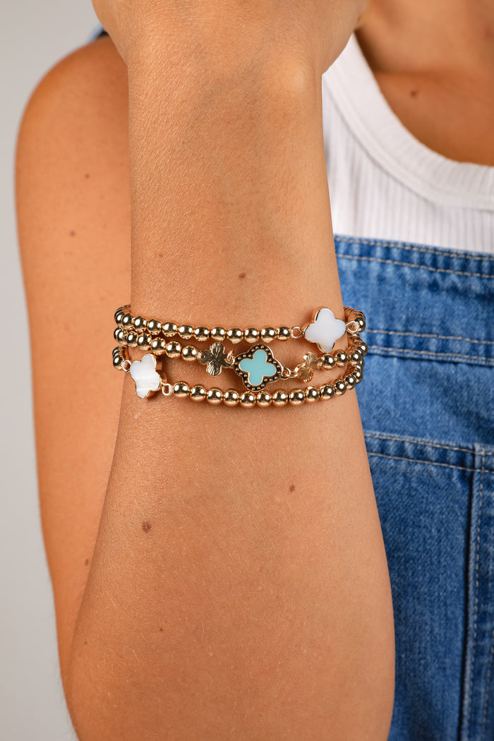 Close-up of a person's arm wearing multiple bracelets with star and flower designs.