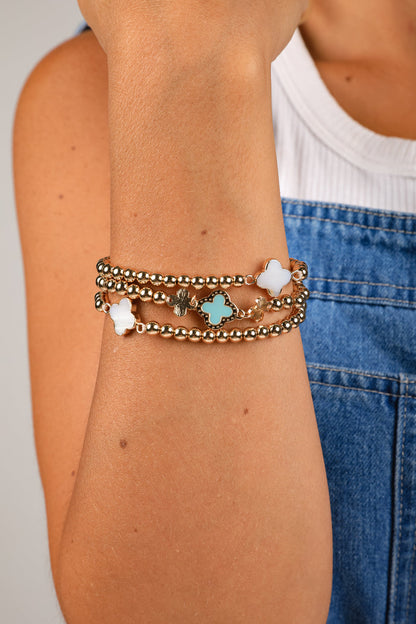 Close-up of a person's arm wearing multiple bracelets with star and flower designs.