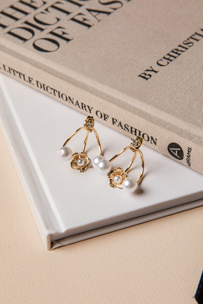Gold earrings with pearls on a book titled 'Little Dictionary of Fashion' by Christian Louboutin.