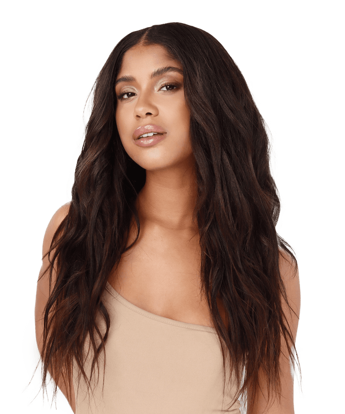 A woman with long, dark brown Relaxed Straight Perfect Crown Hair Extensions by Perfect Locks in a beige one-shoulder top poses confidently against a plain white background, looking at the camera.