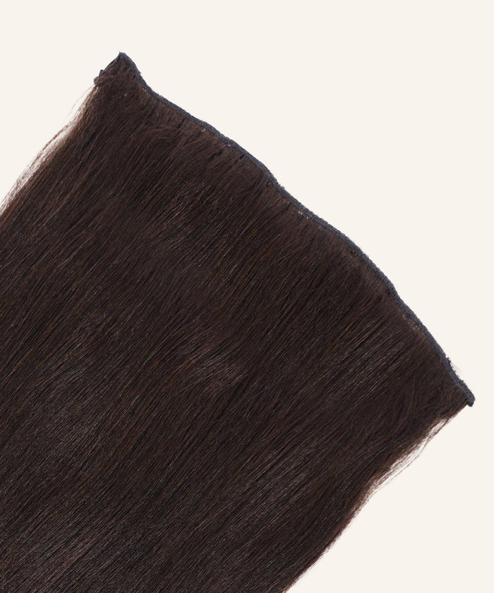 A close-up of Relaxed Straight Perfect Crown Hair Extensions in natural black by Perfect Locks against a light background.#color_natural-black-(1B)