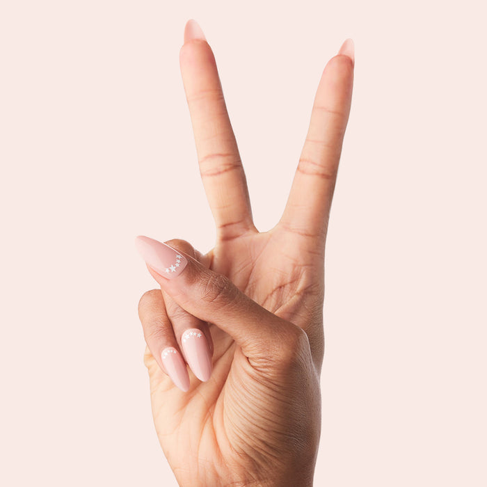 Star Halfmoon - Press-On | Long | Almond showing hand with long almond press-on nails in soft nude with delicate white star halfmoon mani