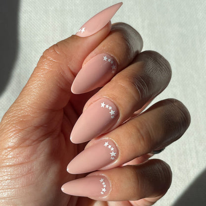 Star Halfmoon - Press-On | Long | Almond showing hand with long almond press-on nails in soft nude with white star detail mani