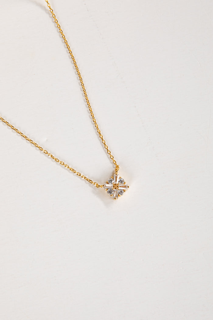 Gold necklace with a star-shaped pendant on a light gray background