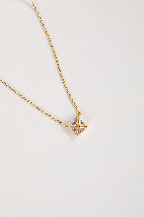 Gold necklace with a star-shaped pendant on a light gray background