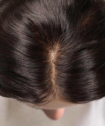 Top view of a person's scalp with a visible part in dark brown hair, highlighting thinning near the center.