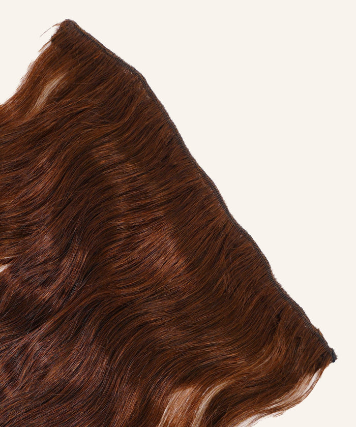A close-up of Wavy Perfect Crown Hair Extensions from Perfect Locks in Warm Mocha Lowlights, laid flat on a light background.#color_chocolate-brown-(3)