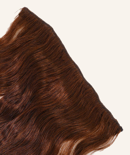 A close-up of Wavy Perfect Crown Hair Extensions from Perfect Locks in Warm Mocha Lowlights, laid flat on a light background.#color_chocolate-brown-(3)
