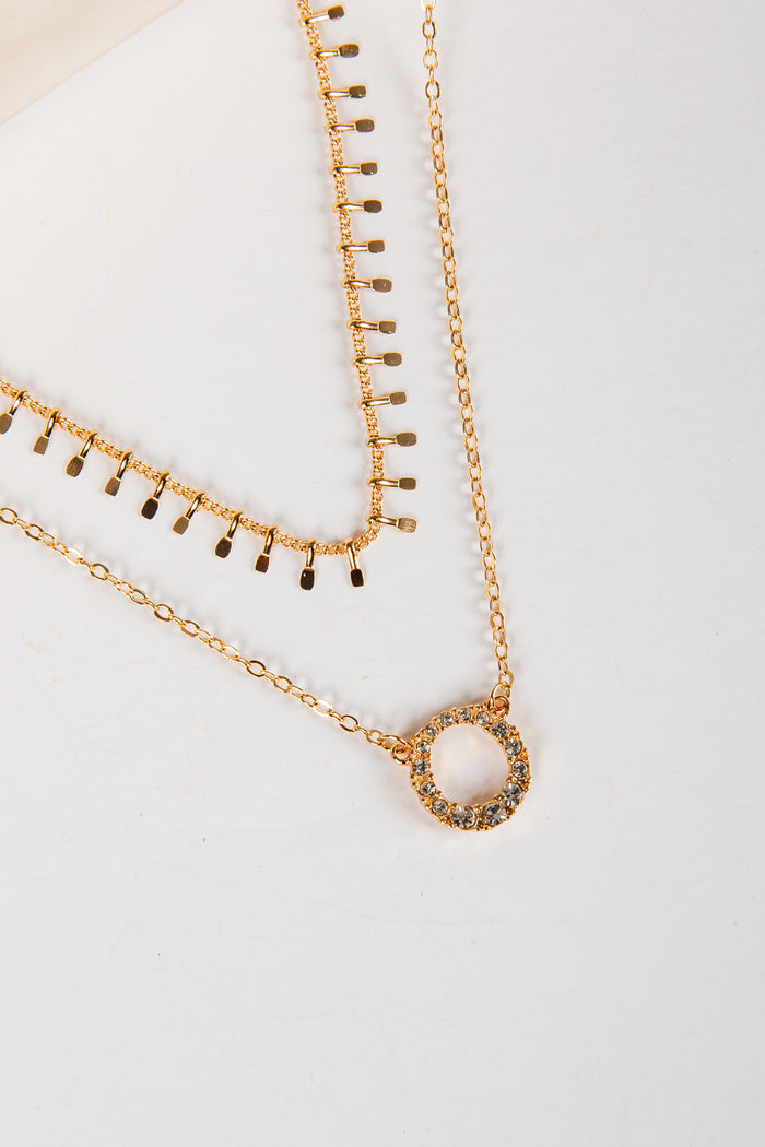 Two gold necklaces on a light gray background